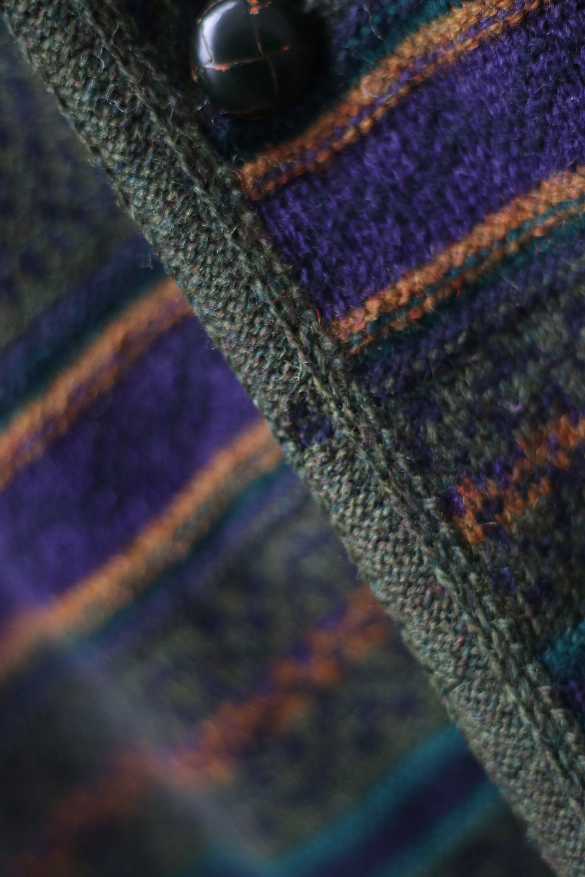 Close up of multi-colored cardigan with green, orange, and purple stripes . The long-sleeved vintage design can be worn as a coat and it is perfect for fall and winter fashion.