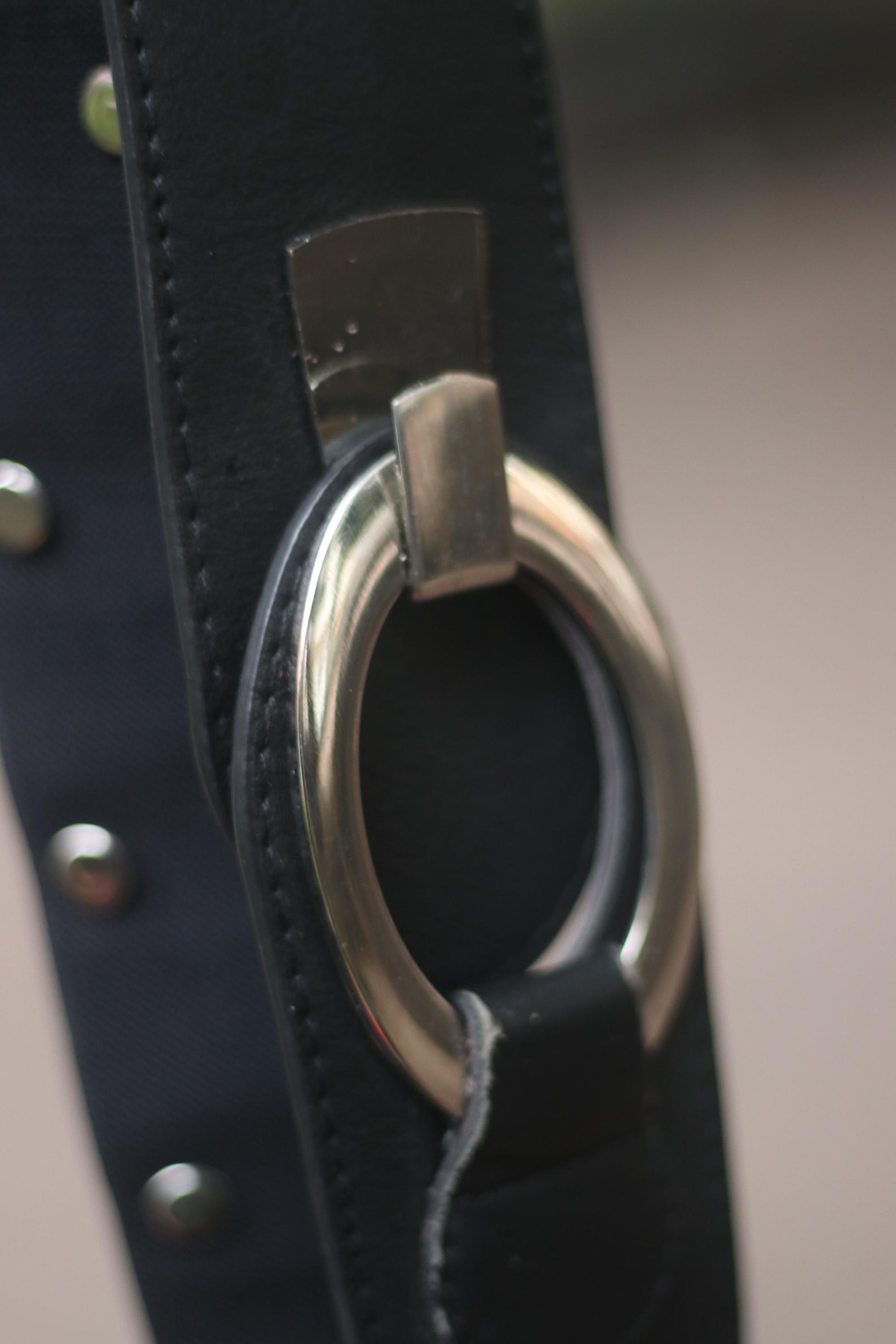 Close up of a black leather belt with silver rivets and buckle