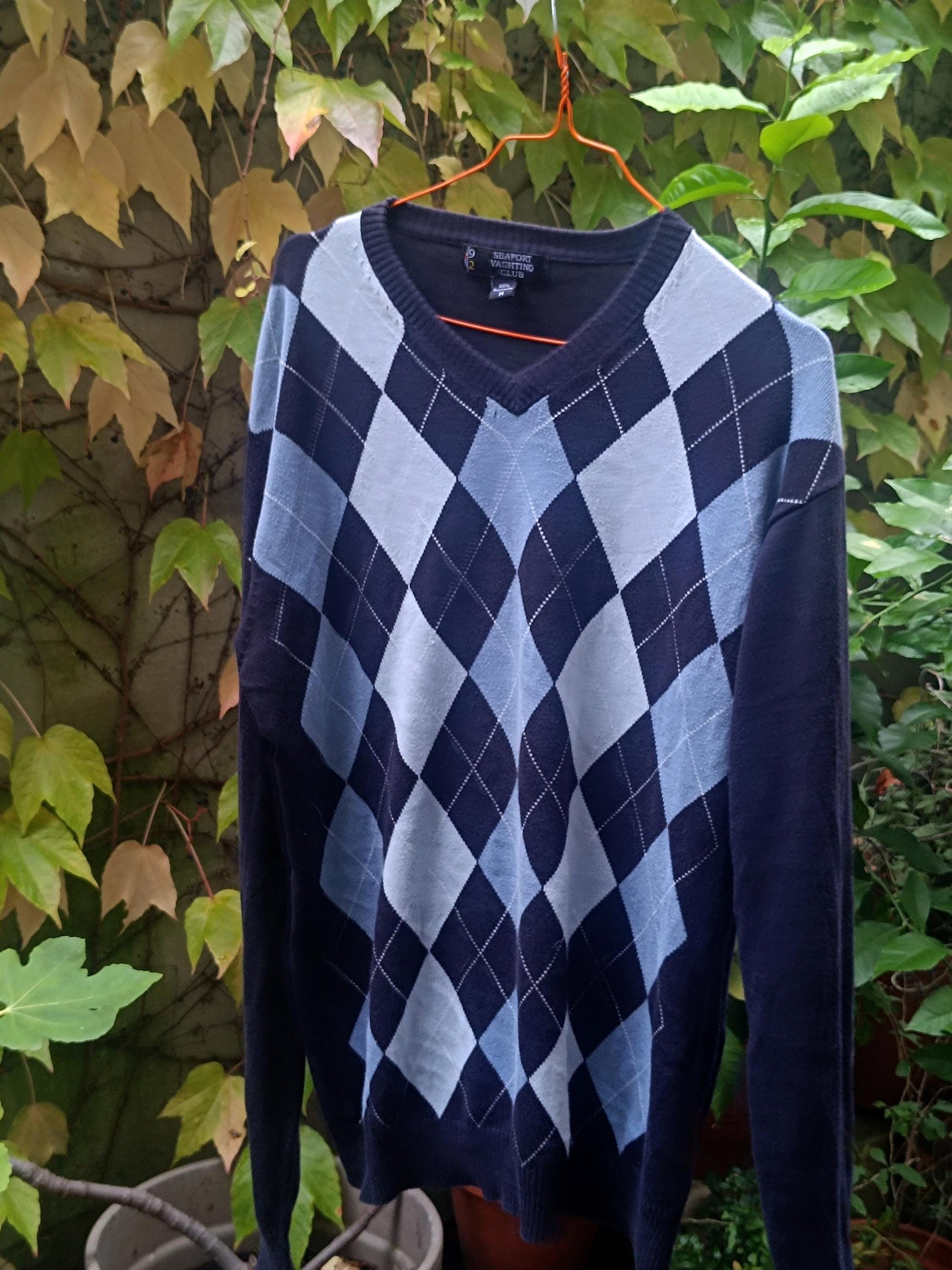 Close-up of the argyle pattern on a vintage blue sweater, showing diamond shapes in blue, gray, and white with contrasting lines, highlighting the intricate knit texture