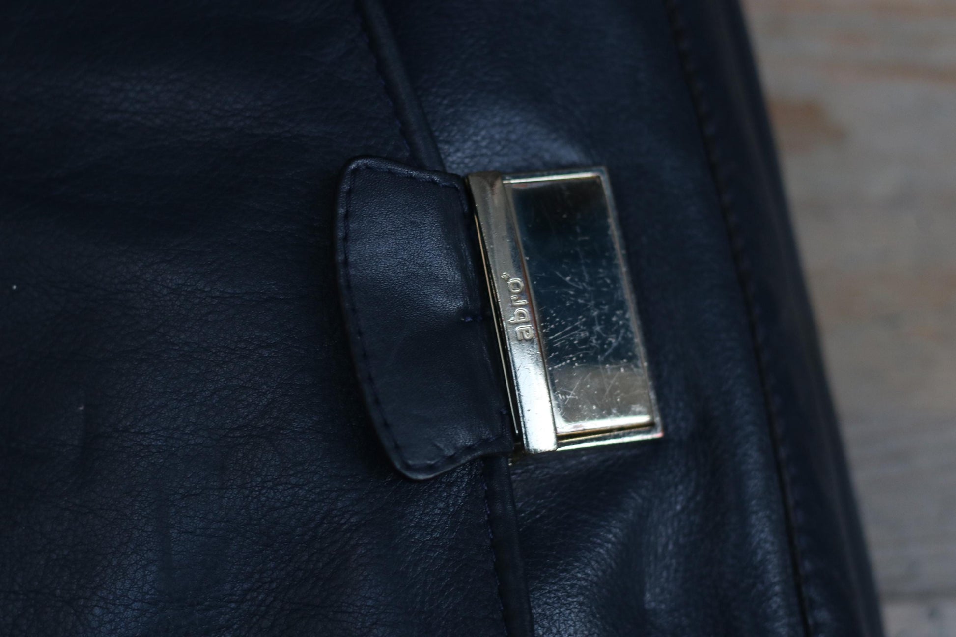 Close-up of a 90s black genuine leather shoulder/crossbody bag . The focus is on the silver-toned clasp showing the brand name, Abro